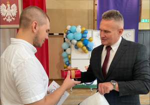 Nauczyciel wręcza nagrodę uczniowi