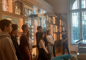 uczniowie słuchający wykładu przy gablotach w salonie ekonomicznym NBP