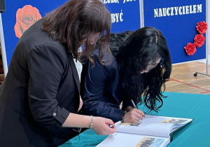 Wychowawca i uczennica składające podpis w kronice