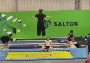 Uczniowie skaczący na trampolinach.