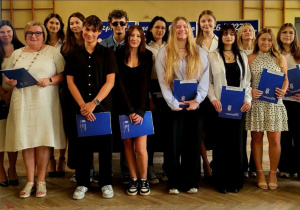 Wręczenie uczniom certyfikatów Europass po zakończeniu projektu Erasmus+. Uczniowie odbierają dokumenty podczas uroczystości.