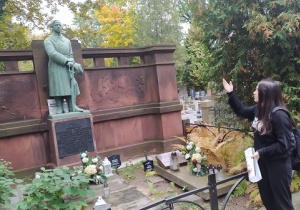 Uczennica prezentuje postać Benedykta Grzymały-Pęczkowskiego przy jego nagrobku na Starym Cmentarzu w Łodzi.