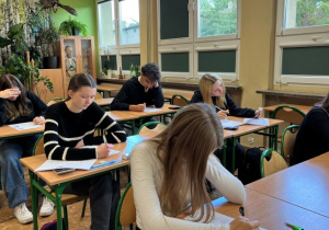 Uczniowie siedzą w ławkach lekcyjnych i rozwiązują test podczas pierwszego etapu eliminacji